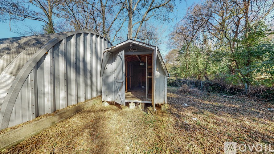 A large metal structure with a door open in the middle of a field.
