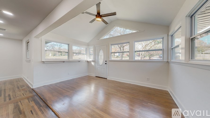 A room with a ceiling fan and large windows.