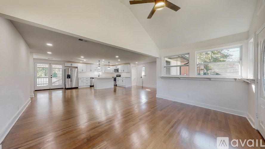 A spacious room with wooden floors and a ceiling fan.
