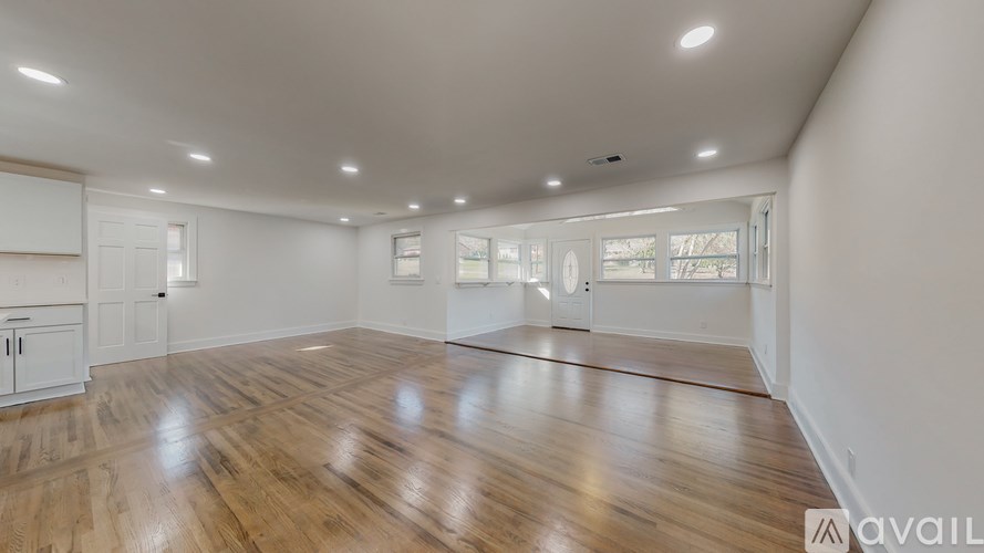 A spacious room with wooden flooring and white walls.