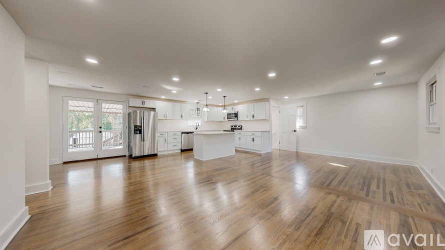 A spacious kitchen and living room with wooden floors and white walls.