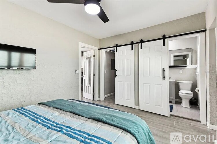 A bedroom with a bed and a bathroom in the background.