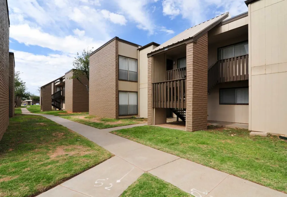 an exterior view of three apartment buildings with grass and sidewalks
