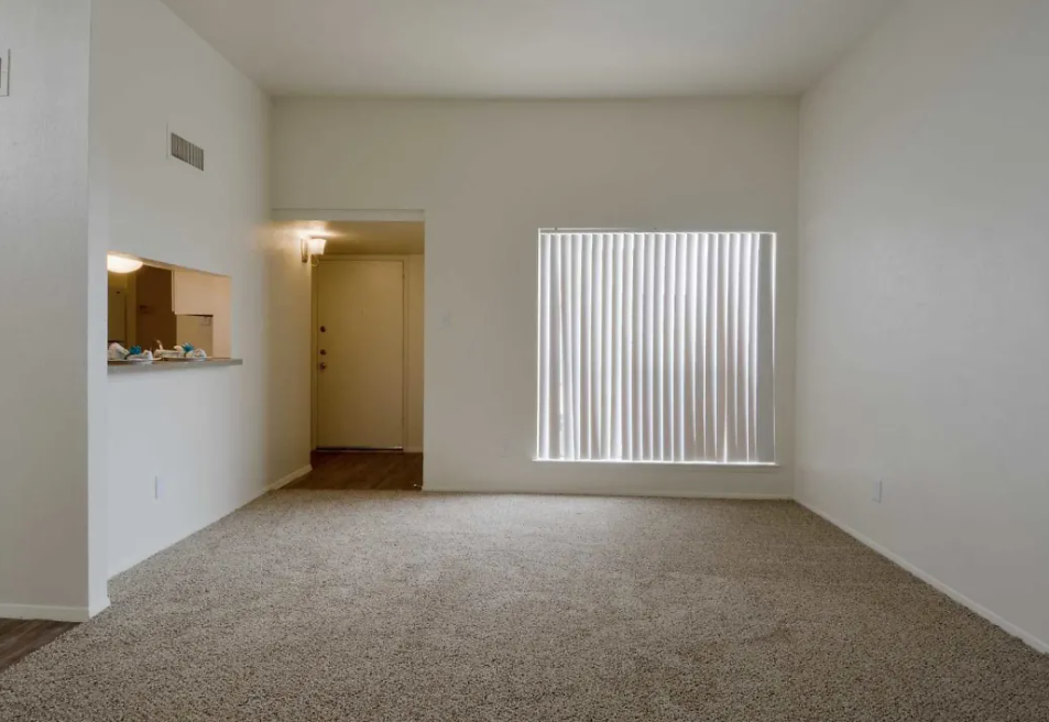 a living room with a large window and a carpeted floor