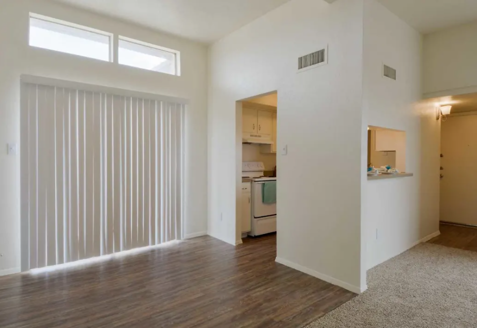 an empty living room with a sliding glass door to the kitchen