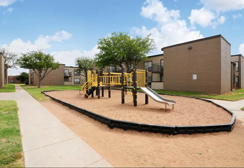 a playground with a slide and sandbox in front of an apartment building