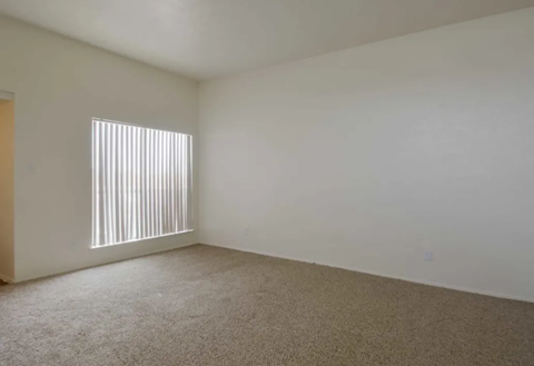 an empty living room with a window and white walls