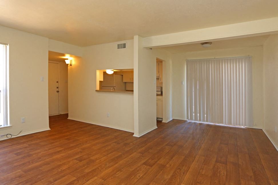 an empty living room with wood flooring and a sliding glass door