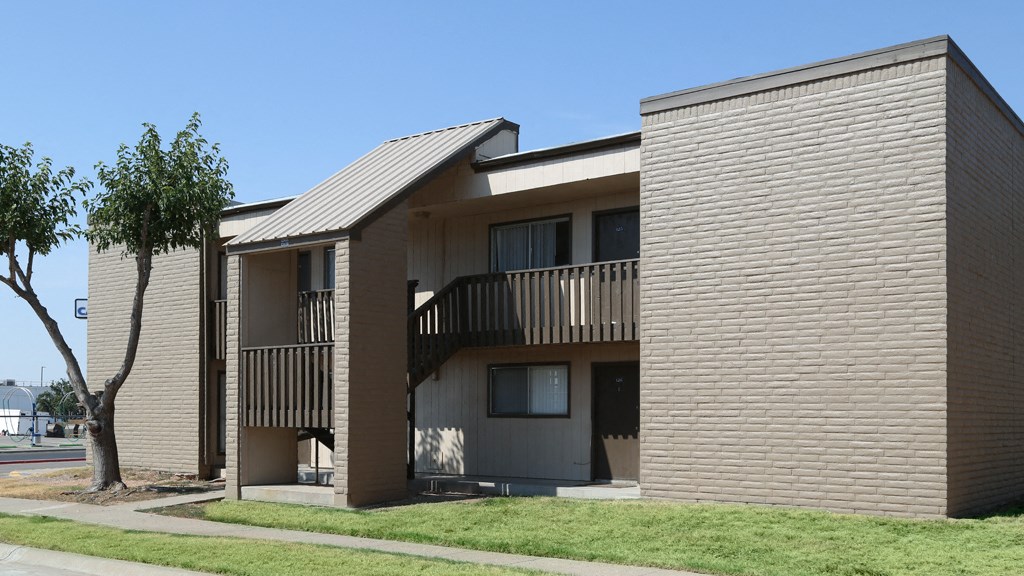 the exterior of an apartment building with balconies and a tree