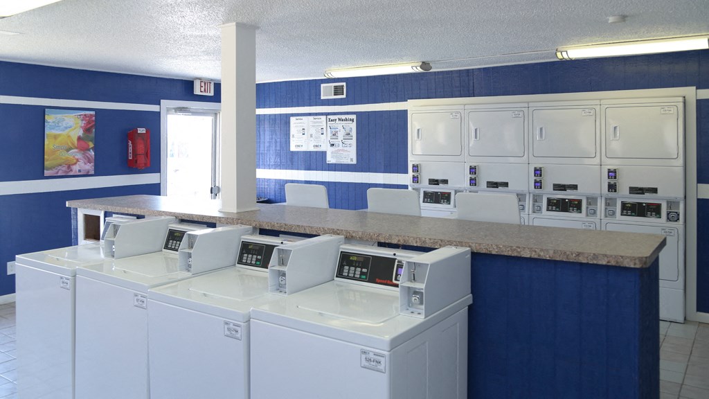 a laundry room with four washing machines and a counter with a row of washes