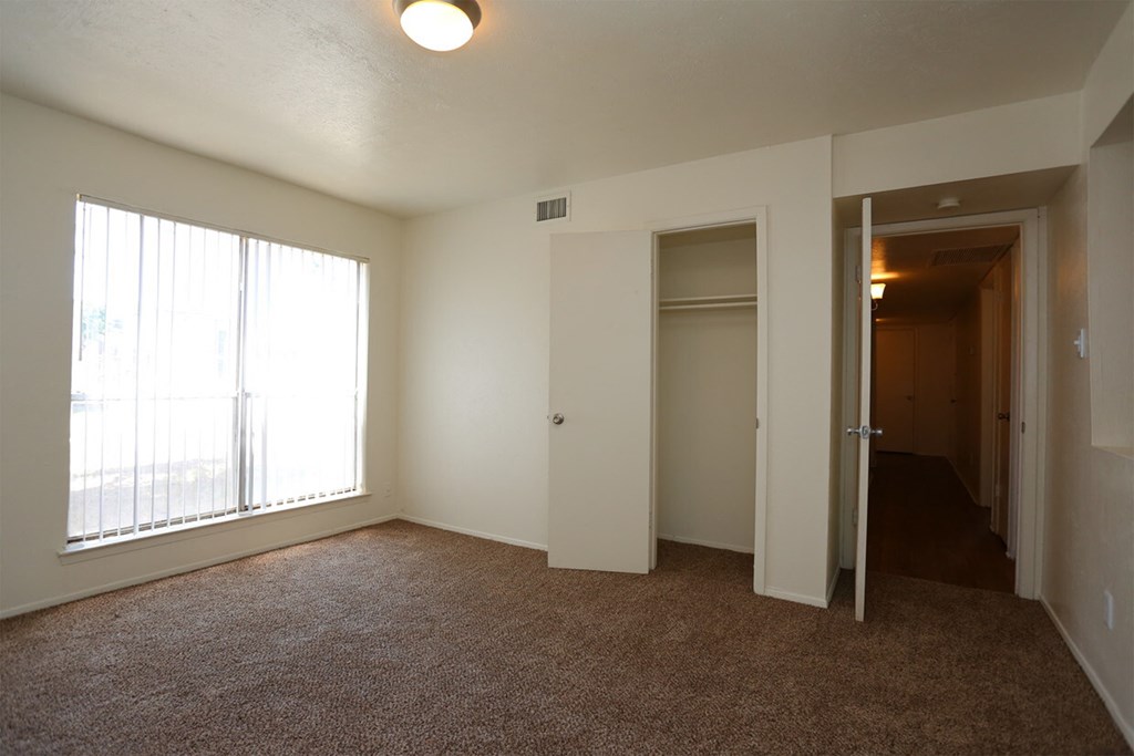 an empty living room with a large window and a closet