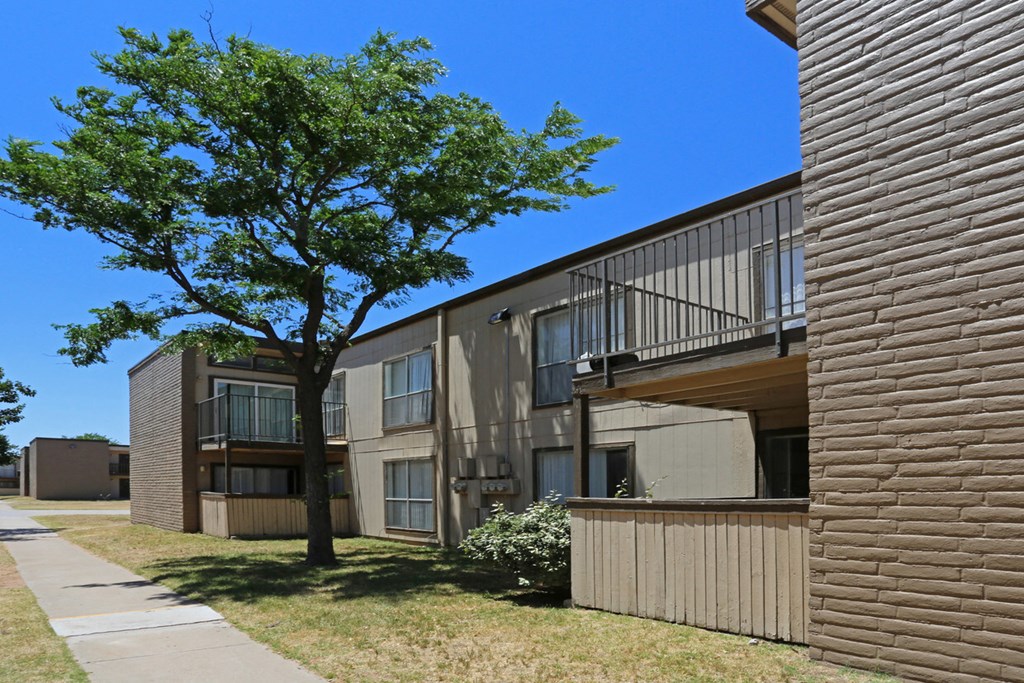 an exterior view of an apartment building with a tree