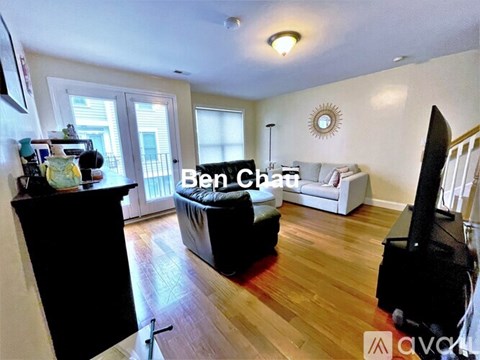 A living room with a black sofa and a wooden floor.