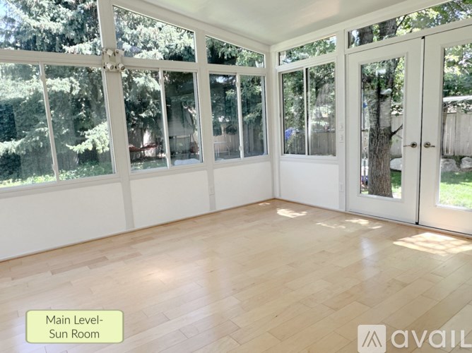A sunroom with wooden floors and white walls.