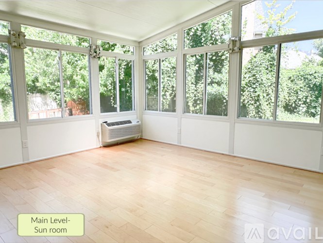 A sunroom with a wooden floor and large windows.