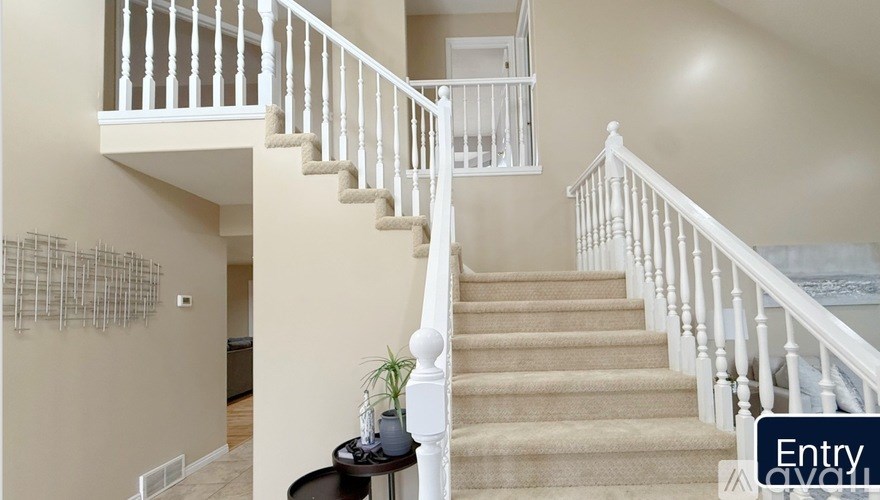 A staircase with a white railing and beige carpet.