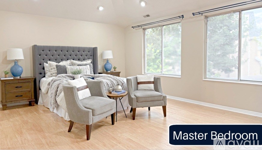 A bedroom with a bed, two chairs, and a nightstand.