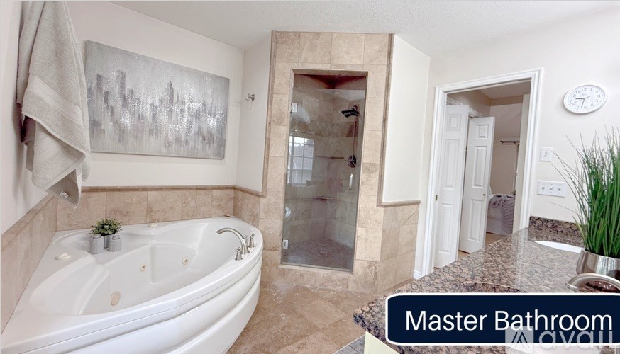 A master bathroom with a large tub and a glass shower.