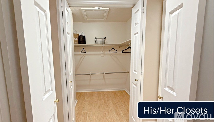 A small closet with clothes hanging on hangers.