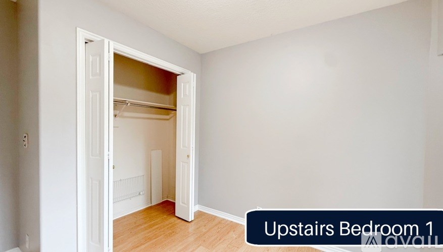A white upstairs bedroom with a door open to a hallway.
