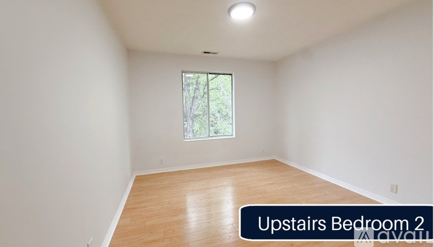 A bedroom with a window and wooden flooring.