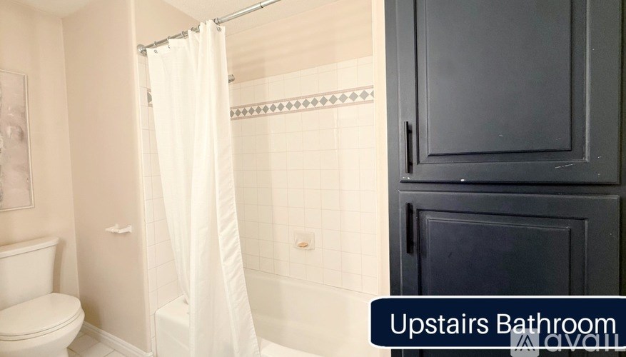 A white bathroom with a toilet, shower, and a cabinet.