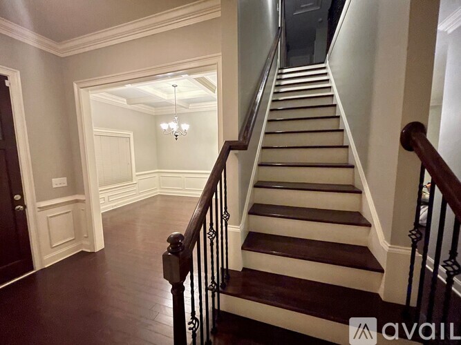 A staircase with a chandelier in the middle of the hallway.