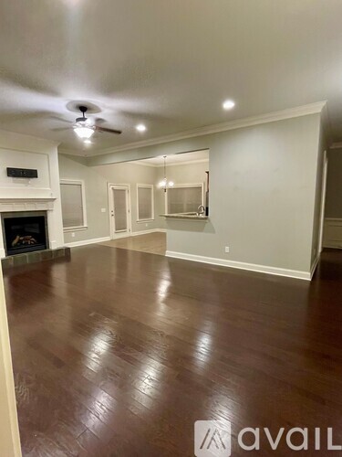 A spacious room with a fireplace and wood flooring.