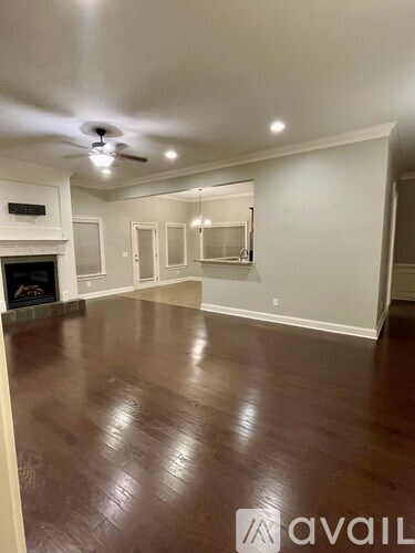 A spacious room with a fireplace and wood flooring.