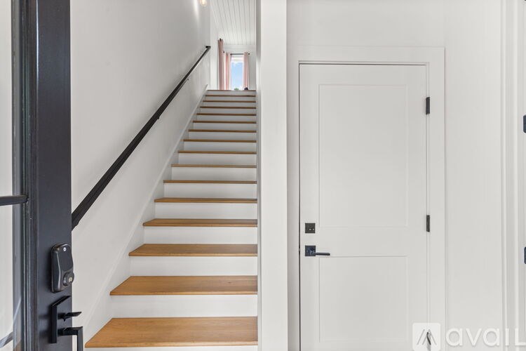 A staircase with wooden steps and a black handrail.
