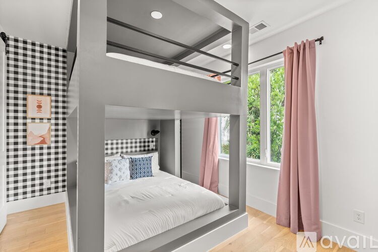 A bedroom with a bed, pink curtains, and a black and white checkered wallpaper.