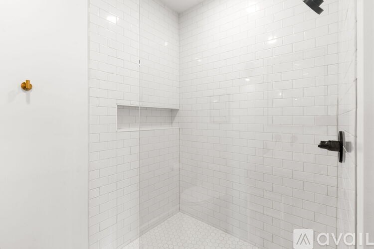 A white tiled bathroom with a door on the right.