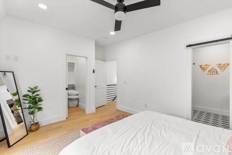 A bedroom with a bed, a ceiling fan, and a mirror.