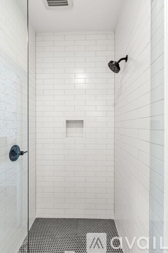 A white tiled bathroom with a black and white floor mat.