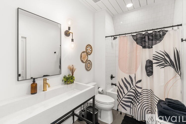 A bathroom with a white sink, toilet, and a mirror with a black frame.