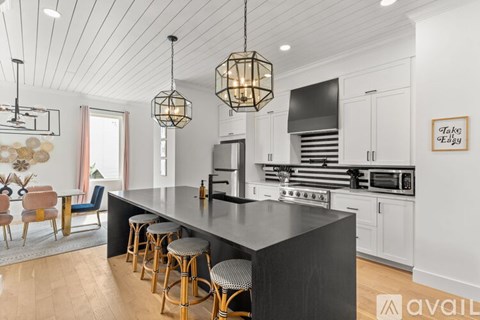 A kitchen with a black countertop and wooden bar stools.