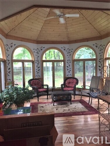 A living room with a wooden ceiling and a piano.