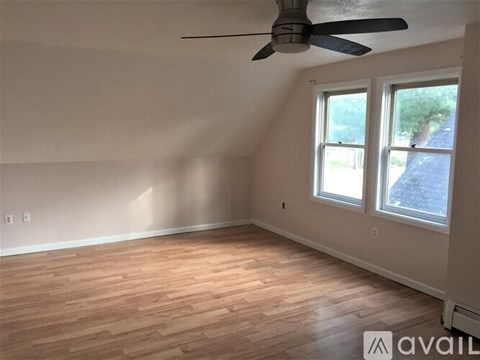 A room with a ceiling fan and wooden flooring.