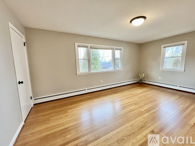 A room with wooden floors and two windows.