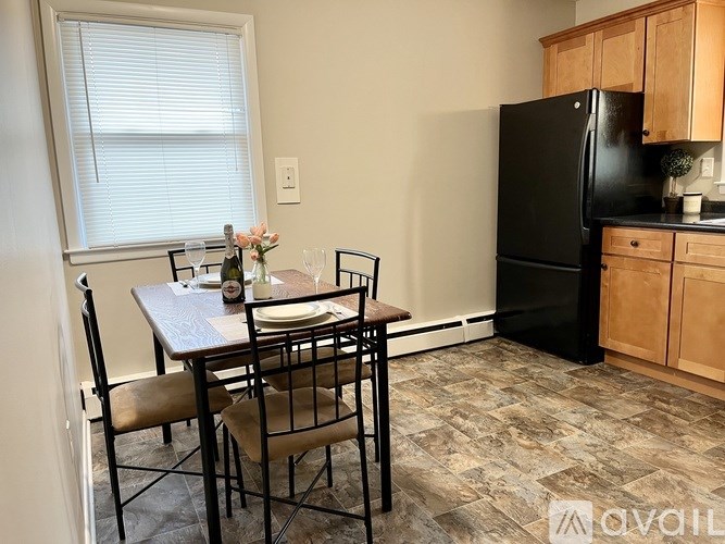 A kitchen with a table set for two and a black refrigerator.