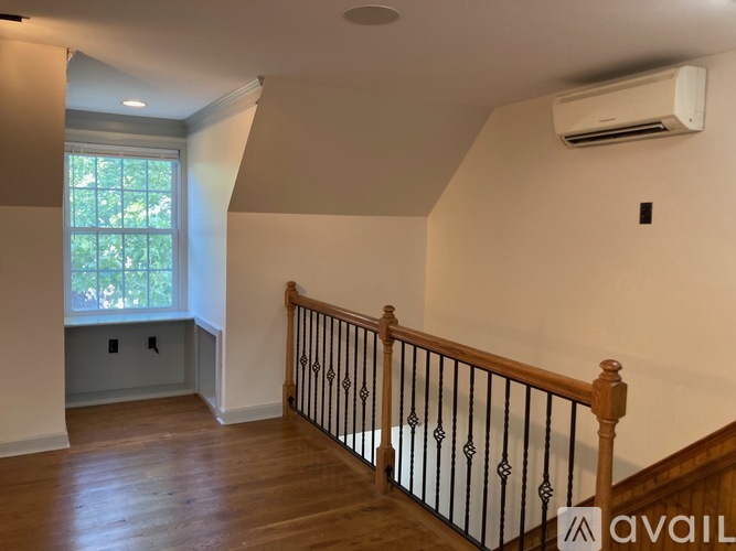 A room with wooden floors and a window with a view of trees.