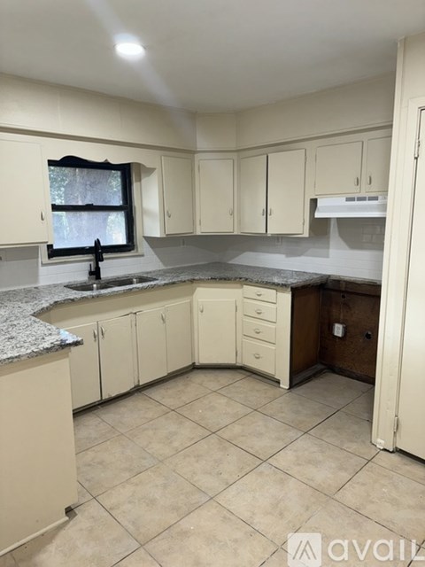 A kitchen with white cabinets and a granite countertop.