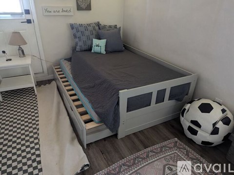A bedroom with a bed, a soccer ball, and a lamp.