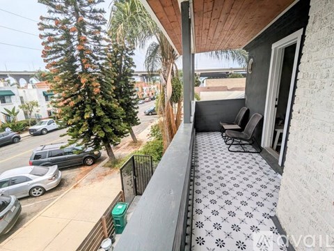 A balcony with a patterned floor and a view of a street with cars and trees.