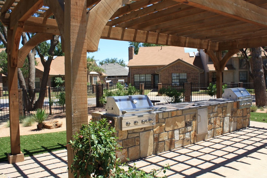 a stone patio with a grill in a backyard