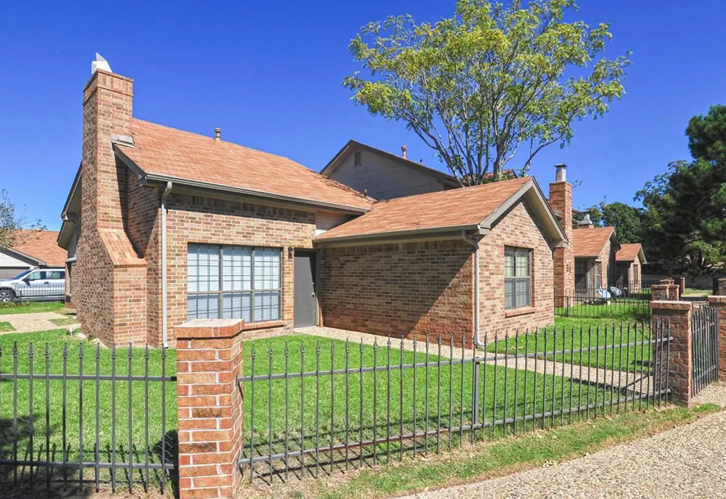 a brick house with a black fence and a yard