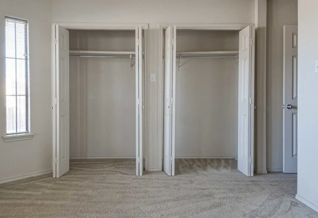 an empty living room with three sliding closet doors