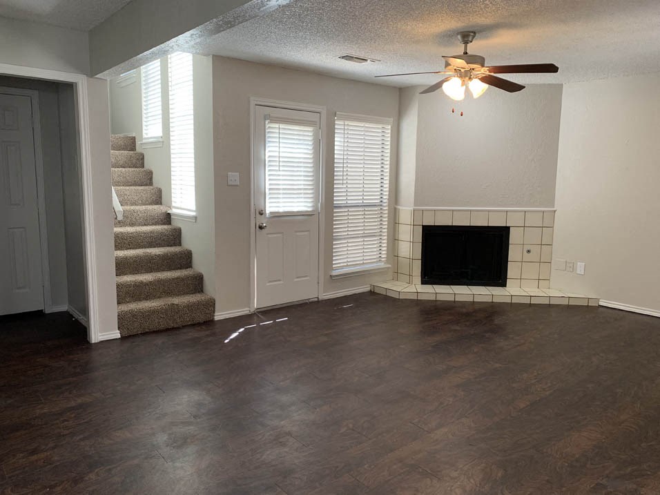 an empty living room with a fireplace and a ceiling fan