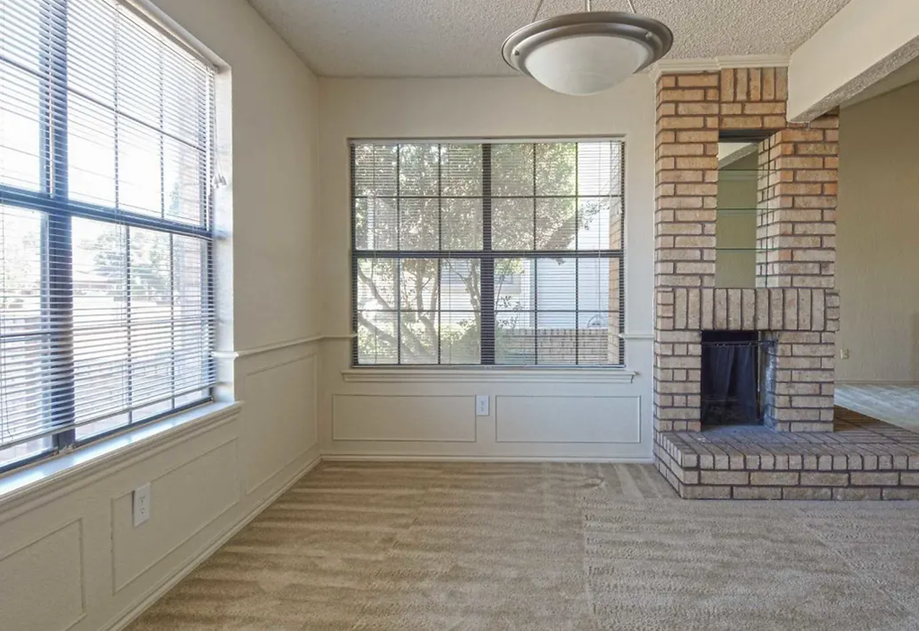 a living room with a brick fireplace and a large window