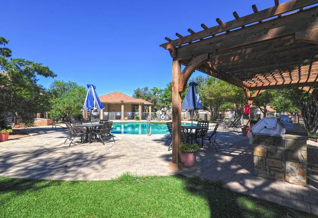 a backyard with a pool and a pavilion with tables and umbrellas